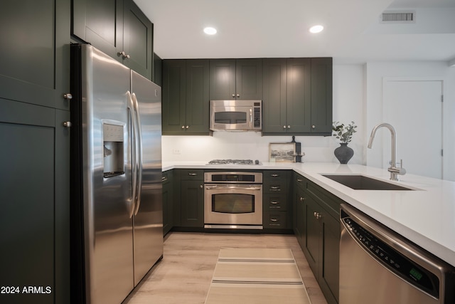 kitchen featuring stainless steel appliances, sink, and light hardwood / wood-style flooring