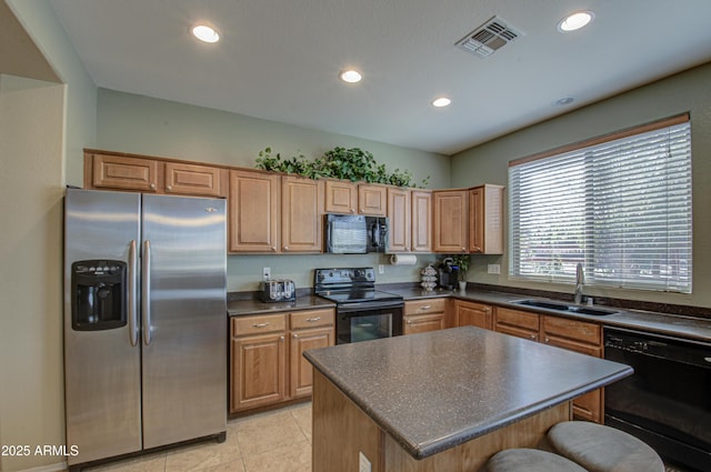 kitchen with dark countertops, black appliances, visible vents, and a sink