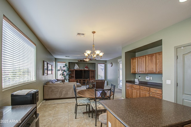 kitchen featuring visible vents, dark countertops, brown cabinets, hanging light fixtures, and a notable chandelier