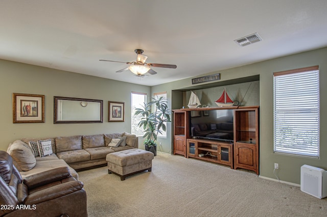 carpeted living room featuring baseboards, visible vents, and a ceiling fan