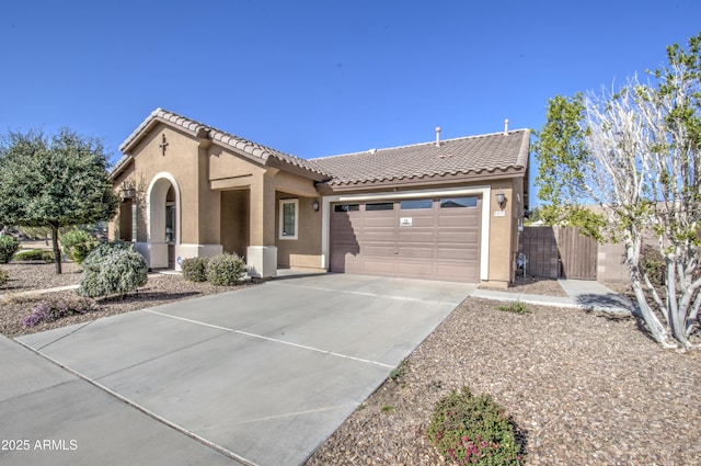 view of front of house featuring a tile roof, stucco siding, concrete driveway, an attached garage, and fence