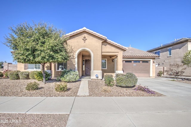 mediterranean / spanish home featuring a garage, driveway, a tile roof, and stucco siding