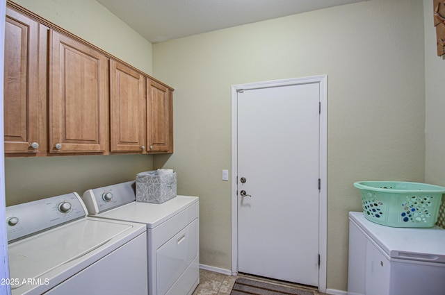 washroom with cabinet space, washing machine and dryer, and baseboards