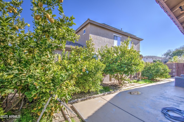 view of side of home with central air condition unit, fence, a patio, and stucco siding