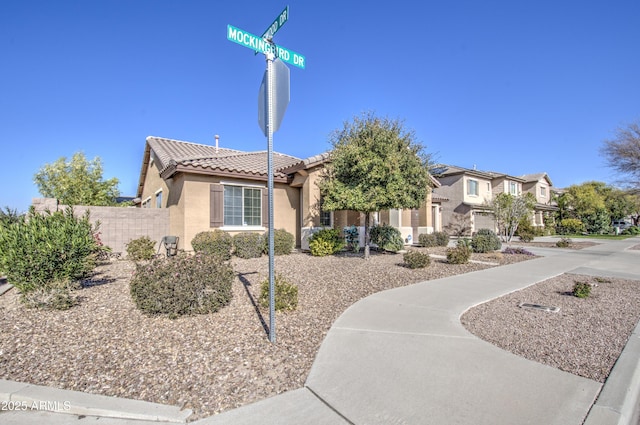 view of front of property with a residential view, fence, a tiled roof, and stucco siding