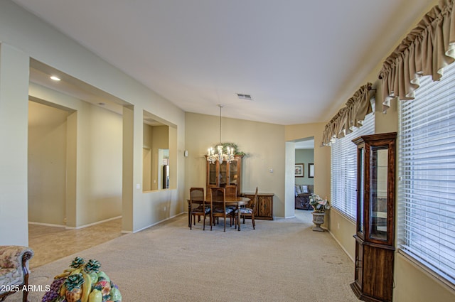 dining space featuring baseboards, carpet, visible vents, and an inviting chandelier