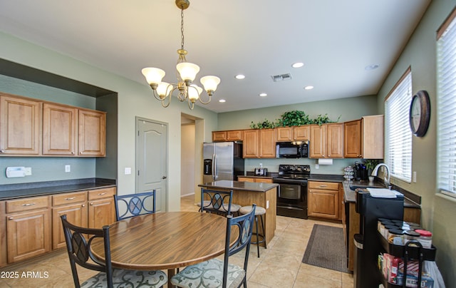 kitchen with light tile patterned floors, visible vents, dark countertops, black appliances, and a sink