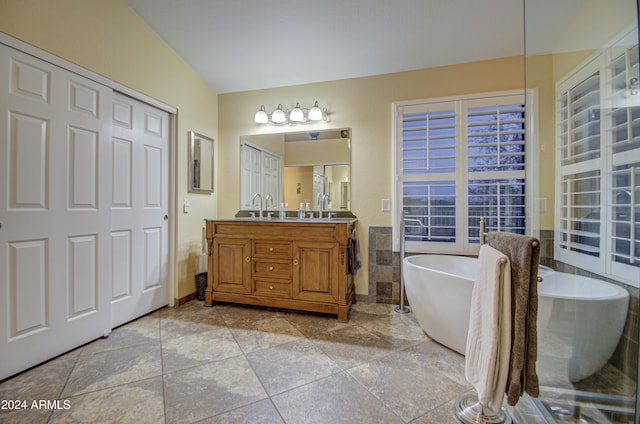 bathroom with vanity, a bathtub, and lofted ceiling