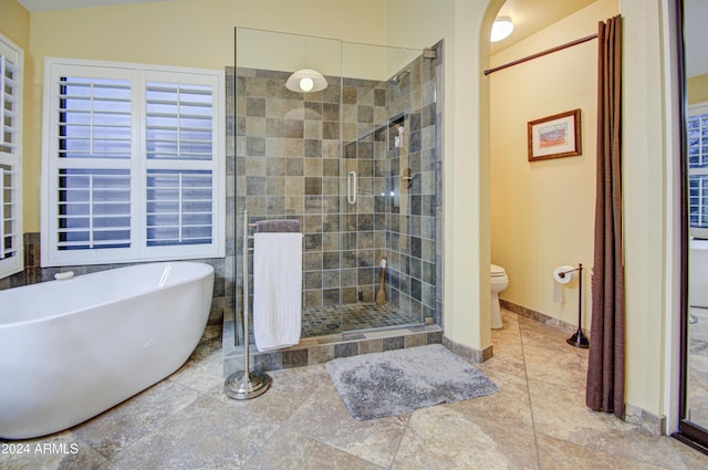 bathroom featuring shower with separate bathtub and toilet