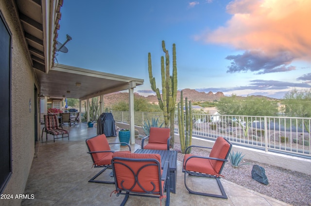 patio terrace at dusk featuring a mountain view and area for grilling