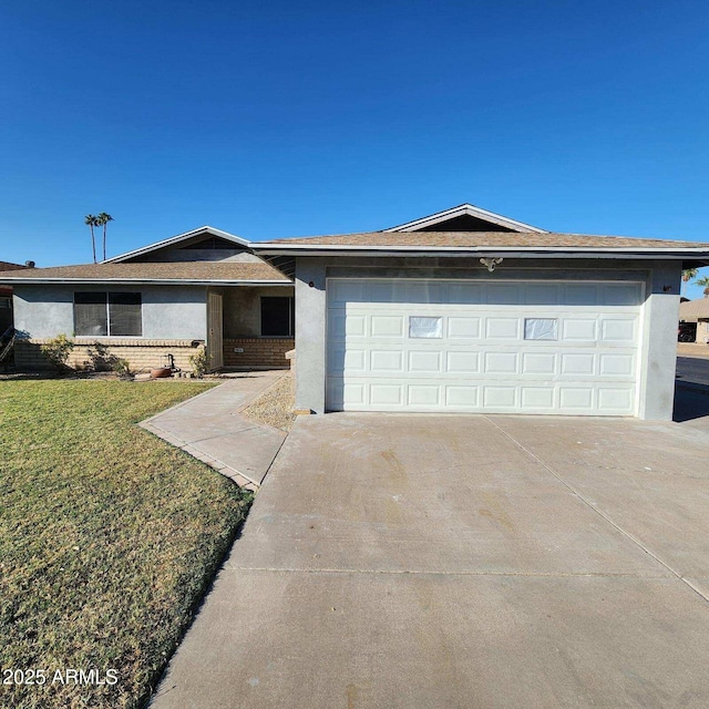 ranch-style home with concrete driveway, stucco siding, an attached garage, brick siding, and a front lawn