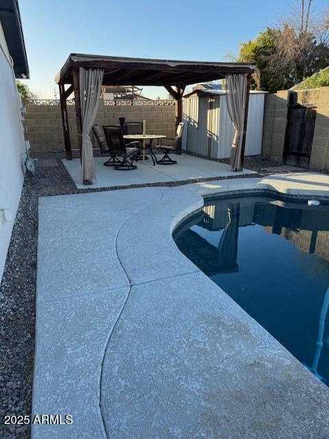 view of swimming pool with a patio, a storage unit, and a fenced backyard