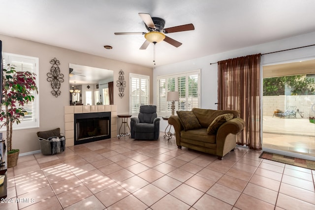 tiled living room with ceiling fan and a tile fireplace