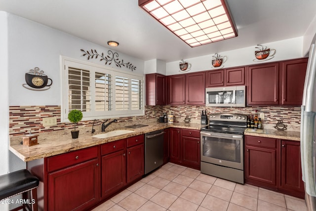 kitchen with sink, stainless steel appliances, light stone counters, decorative backsplash, and light tile patterned floors