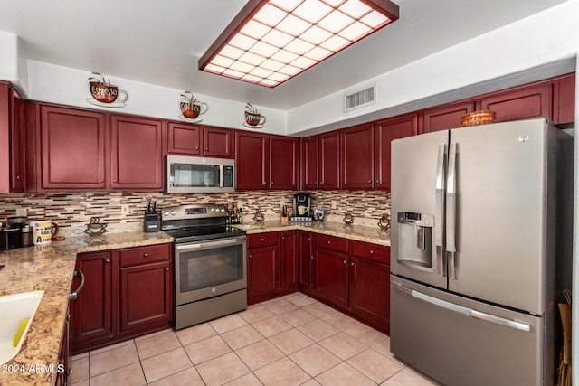 kitchen featuring decorative backsplash, appliances with stainless steel finishes, light stone countertops, and light tile patterned flooring