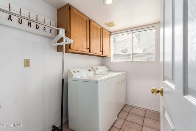 clothes washing area featuring cabinets, light tile patterned floors, and washing machine and dryer