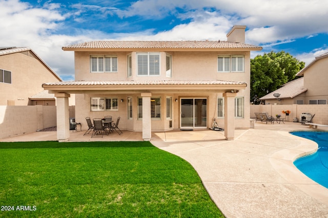 rear view of property with a patio, a fenced in pool, and a lawn