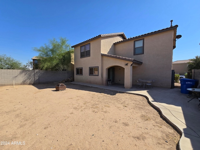 rear view of property featuring an outdoor fire pit and a patio