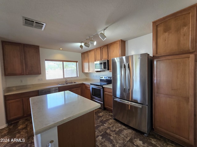 kitchen featuring appliances with stainless steel finishes, sink, a center island, and a textured ceiling