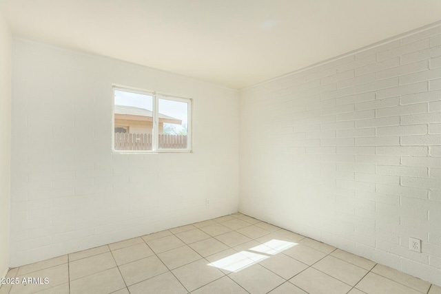 spare room with brick wall and light tile patterned floors