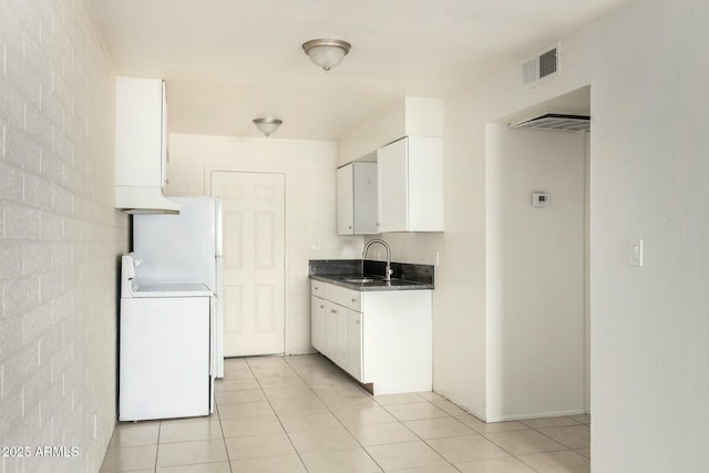 kitchen featuring washer / dryer, range, dark countertops, white cabinetry, and a sink