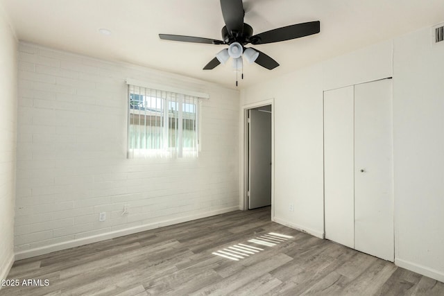 unfurnished bedroom with visible vents, baseboards, a ceiling fan, wood finished floors, and a closet