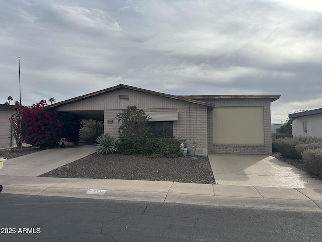 view of front of home featuring an attached carport, brick siding, and driveway