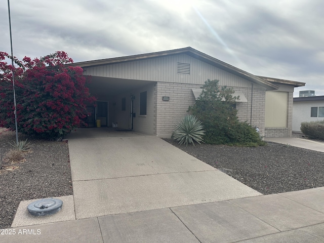 view of front of house with an attached carport, concrete driveway, and brick siding