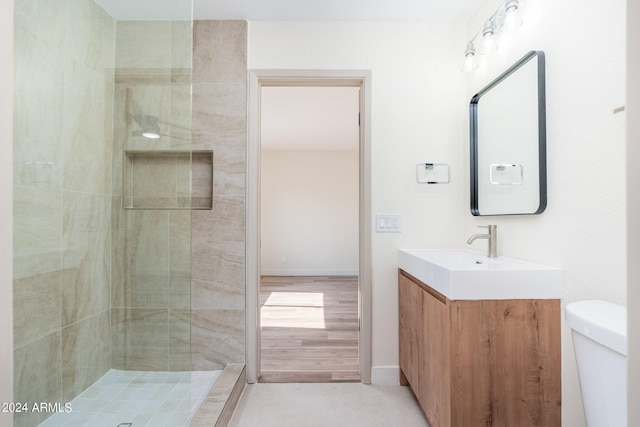 bathroom with vanity, toilet, and a tile shower