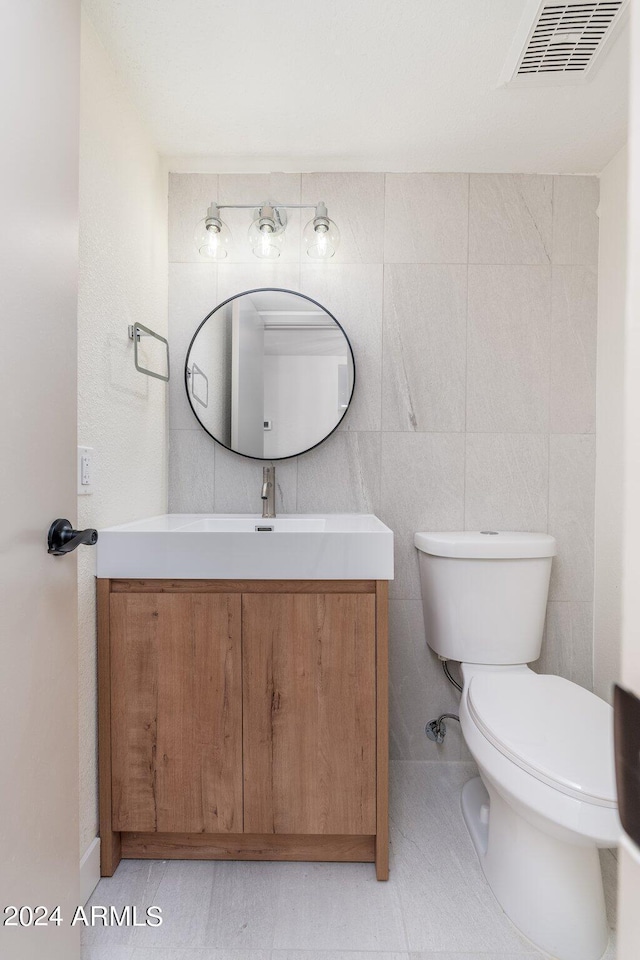 bathroom featuring vanity, tile patterned flooring, tile walls, and toilet