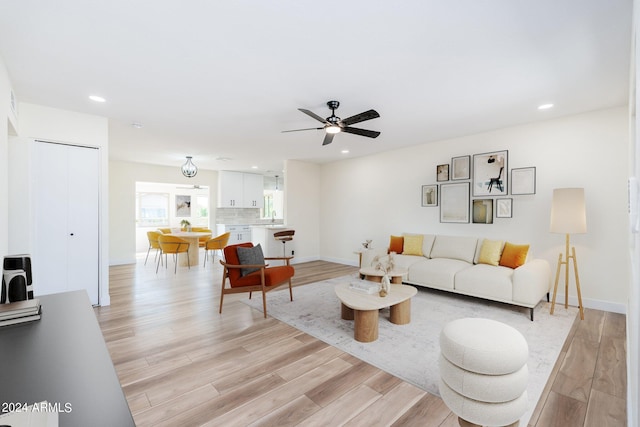 living room with light hardwood / wood-style flooring and ceiling fan