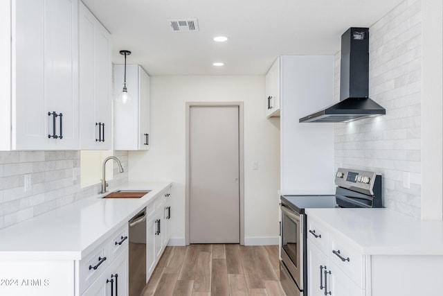 kitchen featuring appliances with stainless steel finishes, pendant lighting, white cabinetry, sink, and wall chimney exhaust hood