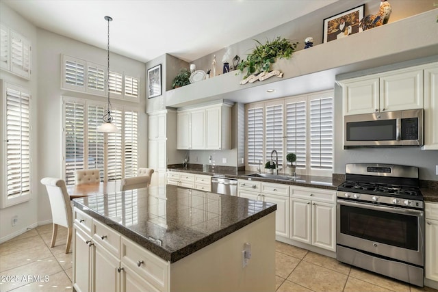 kitchen featuring a kitchen island, stainless steel appliances, sink, hanging light fixtures, and light tile patterned floors