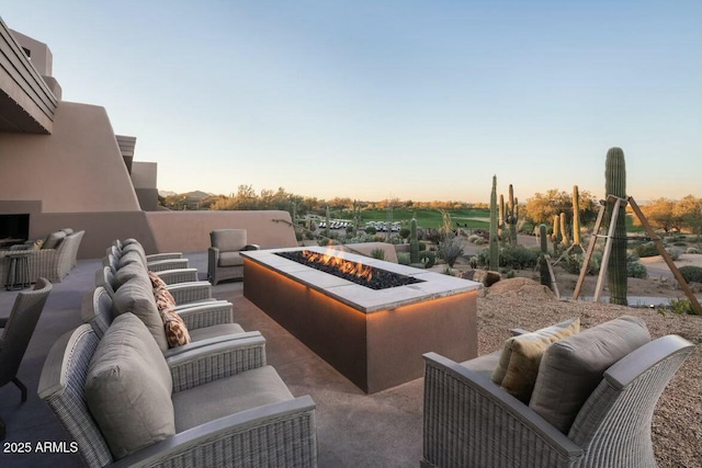 patio terrace at dusk with an outdoor living space with a fire pit