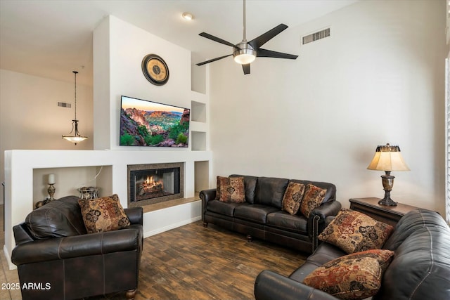 living room featuring vaulted ceiling, ceiling fan, dark hardwood / wood-style floors, and built in shelves