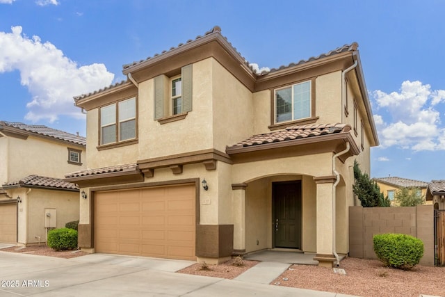 mediterranean / spanish house with concrete driveway, a tile roof, an attached garage, fence, and stucco siding