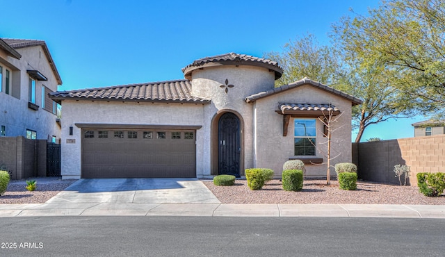 mediterranean / spanish house with a tile roof, fence, concrete driveway, and stucco siding