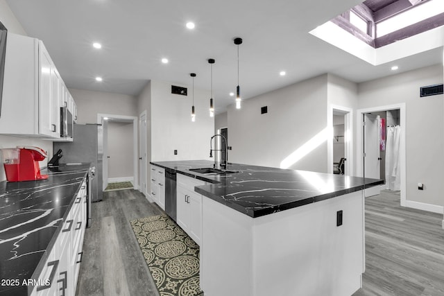 kitchen featuring pendant lighting, a center island with sink, white cabinetry, and stainless steel appliances