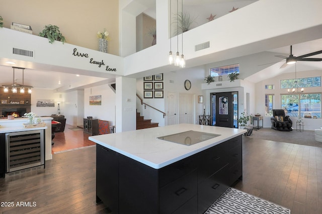 kitchen featuring beverage cooler, hanging light fixtures, a center island, dark wood-type flooring, and black electric cooktop