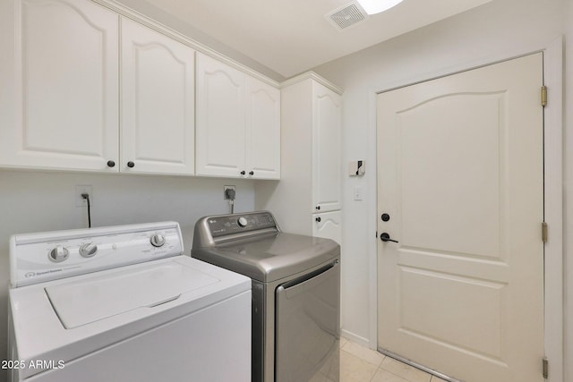 laundry room featuring separate washer and dryer, light tile patterned floors, and cabinets