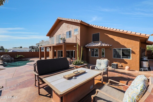 back of house with a balcony, a fenced in pool, and a patio