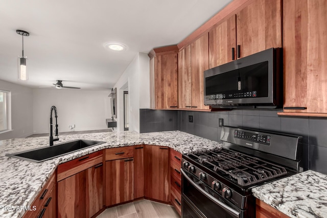 kitchen featuring range with gas cooktop, sink, decorative backsplash, ceiling fan, and light stone counters