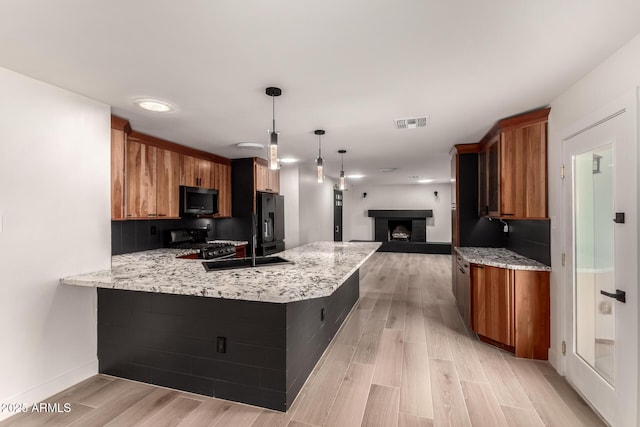 kitchen with range with gas cooktop, kitchen peninsula, hanging light fixtures, and light hardwood / wood-style flooring