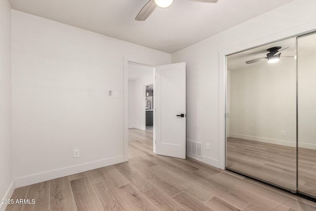 unfurnished bedroom featuring light hardwood / wood-style floors, a closet, and ceiling fan