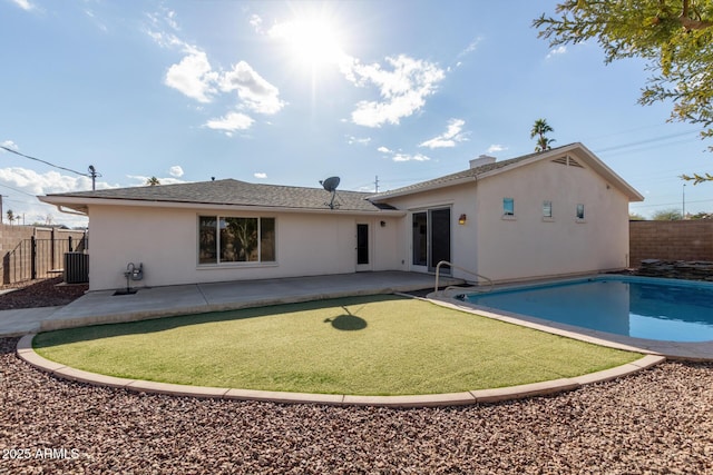 rear view of property featuring a fenced in pool and a patio area