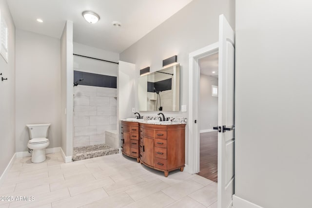 bathroom featuring a tile shower, vanity, and toilet