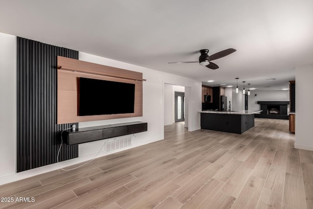 unfurnished living room with ceiling fan and light wood-type flooring