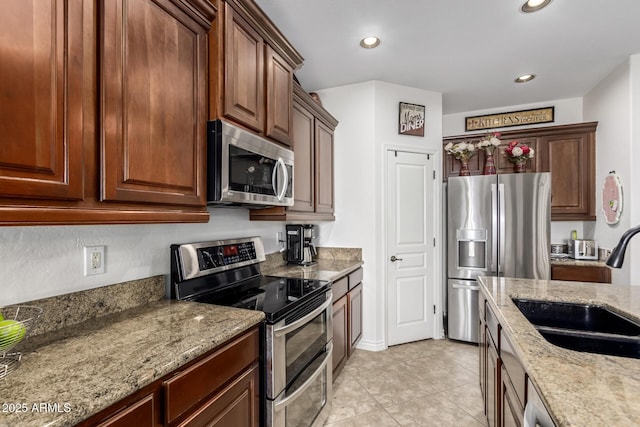 kitchen with light stone countertops, appliances with stainless steel finishes, sink, and light tile patterned flooring