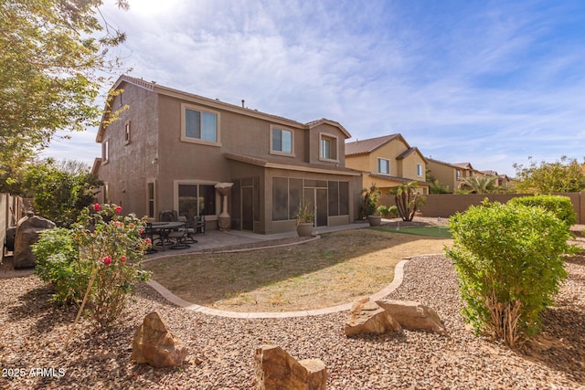 back of property with a sunroom and a patio area