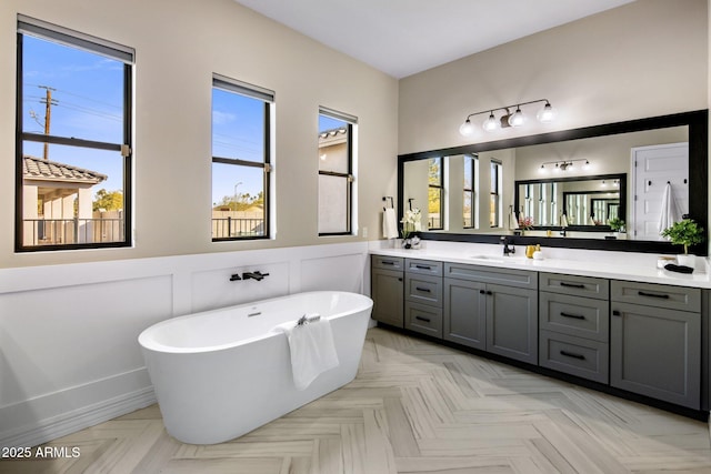 bathroom featuring vanity, a tub, a healthy amount of sunlight, and parquet floors